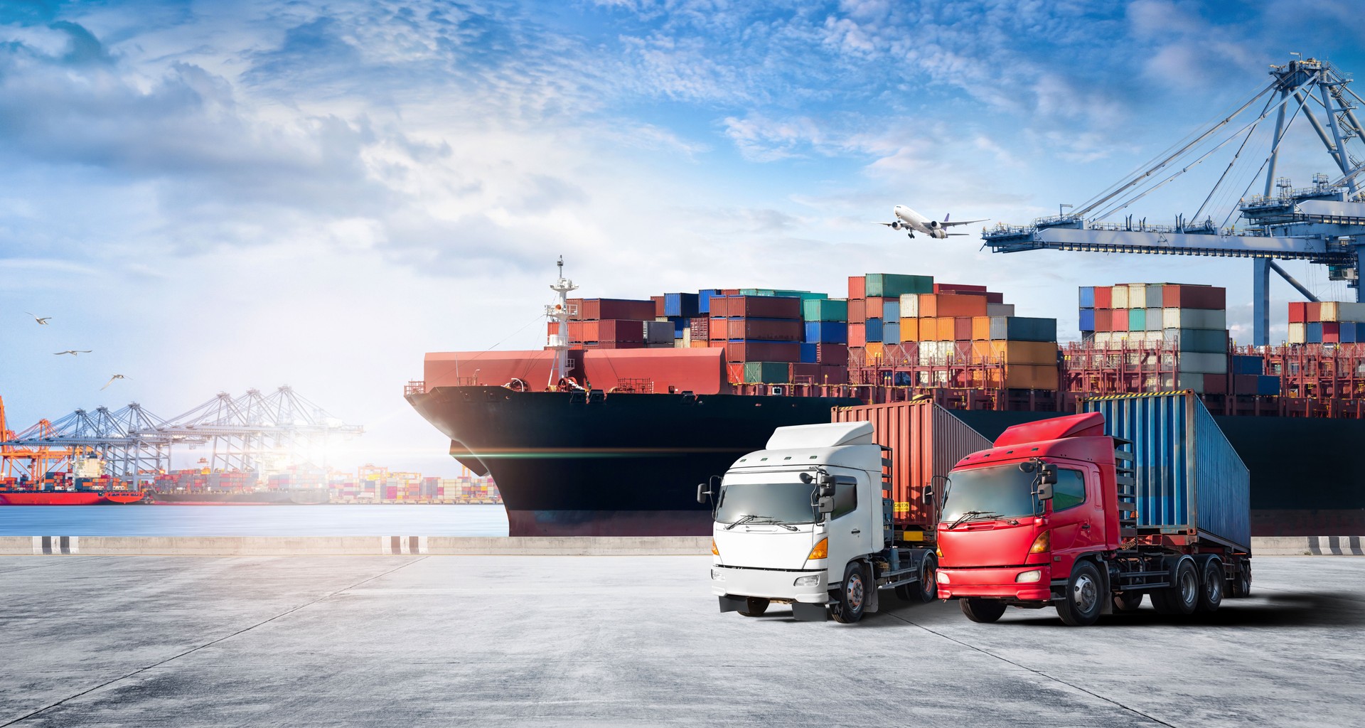 Container cargo freight ship during discharging at industrial port and move containers to container yard by trucks, cargo plane, logistic import export background and transport industry concept
